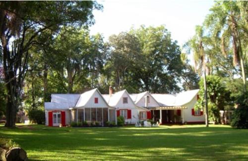 a red and white house in a yard with trees at Estancia Las Mercedes in Eldorado