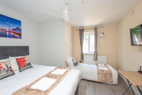a bedroom with two beds and a desk in it at Saffron Studios in Orpington