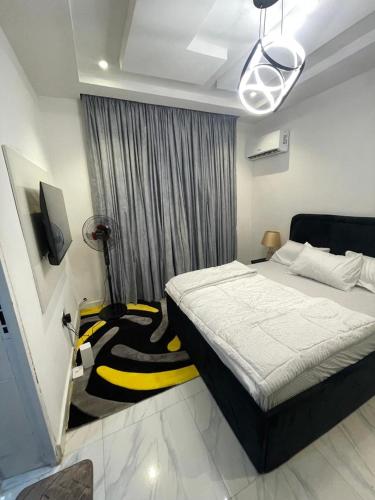 a bedroom with a bed with a black and yellow blanket at DMayors Apartments in Garki