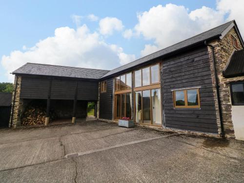 a black house with a garage and a driveway at Hunstone Barn in South Molton