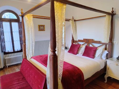 a bedroom with two four poster beds with red pillows at Chavarri Etxea, casa indiana XBI00149 in Biáñez