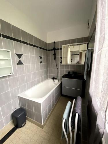 une salle de bain avec une baignoire, un lavabo et un miroir dans l'établissement Appartement 2-4 personnes - Triel Sur Seine, à Triel-sur-Seine