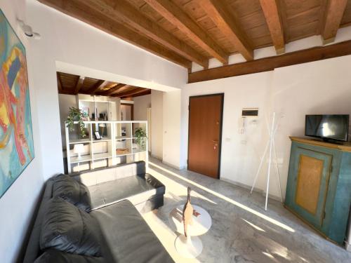 a living room with a black couch and a tv at Casa sulle mura Romane - Old town in Bergamo