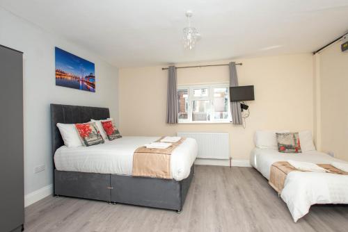 a bedroom with two beds and a window at Saffron Studios in Orpington