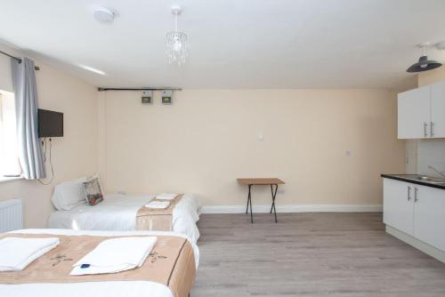 a room with two beds and a table at Saffron Studios in Orpington
