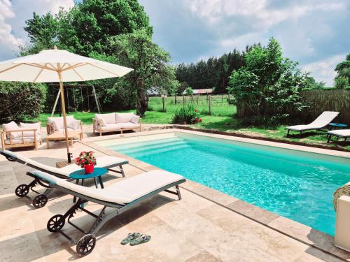 une piscine avec une table et un parasol dans l'établissement Jacuzzi, Piscine, Station de recharge pour véhicule électrique, Maison normande du 19ème Siècle à 25' de Deauville, classée meublé de tourisme 5 étoiles, à Saint-Philbert-des-Champs