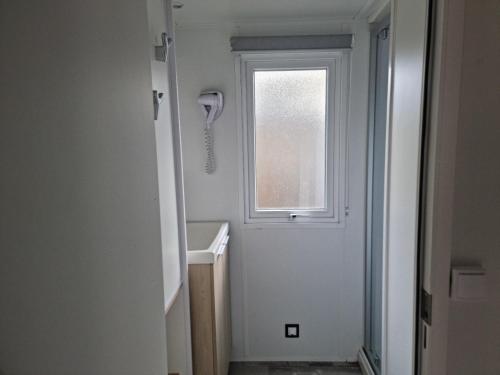 Elle comprend une petite salle de bains pourvue d'une fenêtre et d'un lavabo. dans l'établissement ARDECHE, mobil home 6 personnes climatisé, à Lagorce
