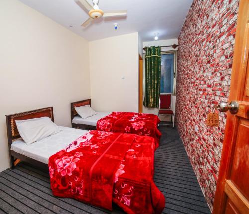 a room with two beds with red sheets and a brick wall at Yak Sarai Hotel & Restaurant in Skardu