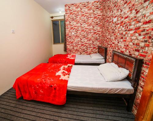 two beds in a room with a brick wall at Yak Sarai Hotel & Restaurant in Skardu