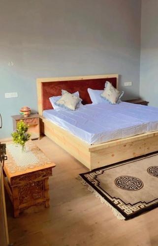 a bedroom with a large bed with a wooden headboard at The apricot house in Leh