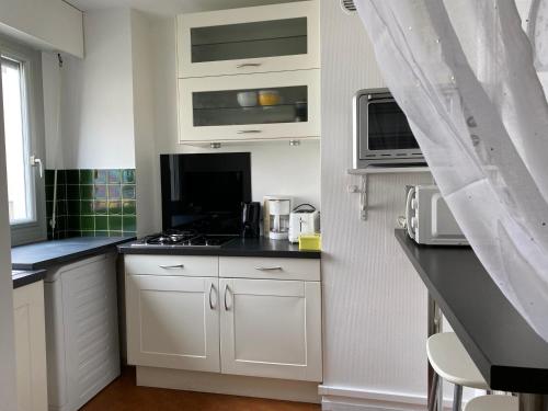 une cuisine avec des armoires blanches et un comptoir noir dans l'établissement Studio Angela proche Tour Eiffel, à Paris