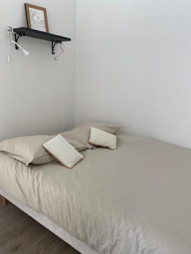 - un lit avec 2 oreillers et une étagère sur le mur dans l'établissement Studio Angela proche Tour Eiffel, à Paris
