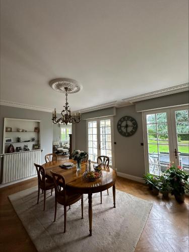 une salle à manger avec une table, des chaises et une horloge dans l'établissement les Tulipes, à Antrain