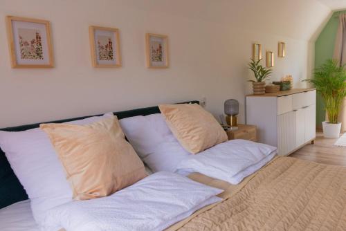 a bed with white sheets and pillows in a room at Nyárfás Panoráma Vendégház in Dunavarsány