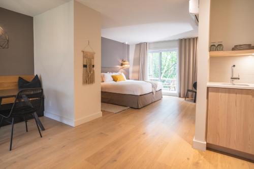 a bedroom with a bed and a desk and a kitchen at Suites du Lac Moore by Manitonga in Mont-Tremblant
