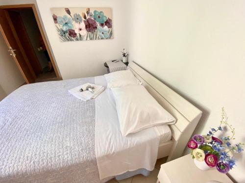a bedroom with a white bed and flowers on a table at Rooms Villa Gala in Mlini