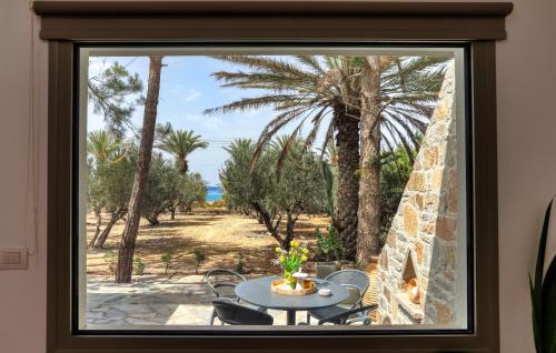 a window view of a patio with a table and palm trees at Lemoni House in Petras, Sitia, by Comfortbnb in Sitia