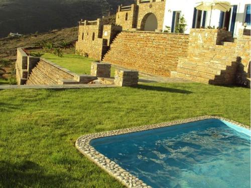 a swimming pool in the grass next to a building at Villa Helen in ayios Petros