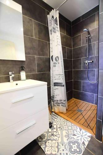 La salle de bains est pourvue d'un lavabo et d'une douche avec rideau de douche. dans l'établissement Charmant appartement calme, avec terrasse fleurie, à Calenzana