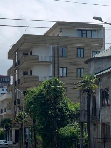a tall building with palm trees in front of it at Penthouse Sea Breeze in K'obulet'i