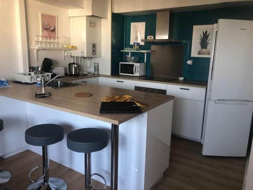 une cuisine avec un comptoir et deux tabourets de bar dans l'établissement T4 lumineux proche hypercentre, à Toulouse