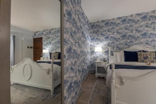 a bedroom with blue and white wallpaper and two beds at 1850 Hotel Boutique in Guanajuato