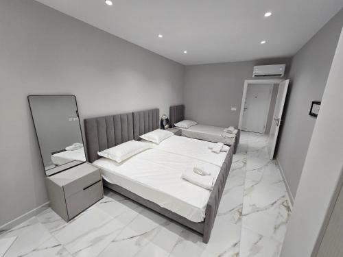 a white bedroom with a bed and two mirrors at Prestige Beach Apartment in Durrës