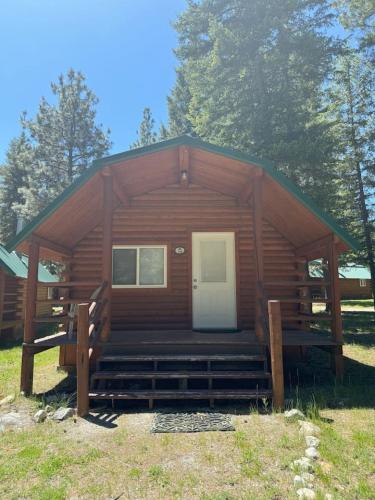 a log cabin with a porch and a white door at Lost Horse Lodge King Cabin 18 in Darby