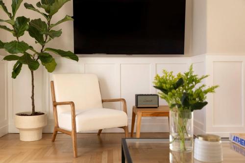 a living room with a chair and a tv on a wall at Meliti Apartment in Plaka in Athens