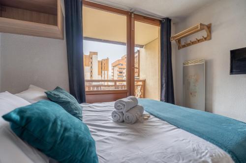 a bedroom with a bed with towels and a window at Ski In-Out - Heart of Val Thorens Modern Apartment, WiFi 93 in Val Thorens