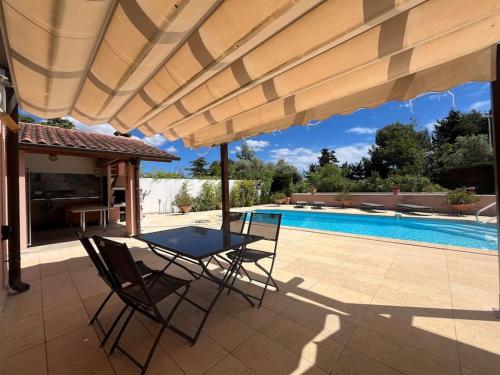 un patio avec une table et des chaises à côté d'une piscine dans l'établissement Magnifique appt T2 avec Piscine, à Saint-Cyr-sur-Mer