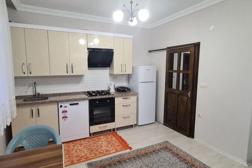 a kitchen with white cabinets and a white refrigerator at Deniz ve Doğa Manzaralı Daire Arsin-Trabzon in Arsin
