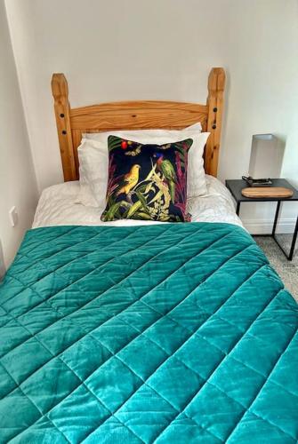 a bed with a green comforter and a side table at The Townhouse in Gainsborough