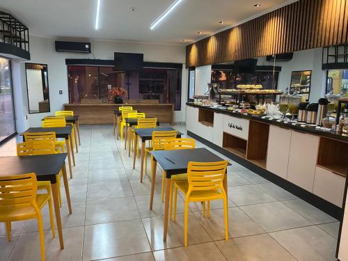 a restaurant with tables and yellow chairs and a counter at HOTEL AVENIDA PLAZA in Querencia