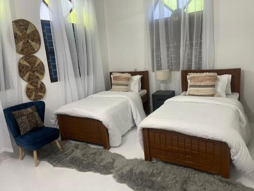 a bedroom with two beds and a blue chair at Nashu House Stone Town in Ngambo
