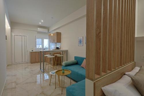 a living room with a blue couch and a kitchen at Gold Waves Luxury Studios by Pieria Riviera in Paralia Katerinis
