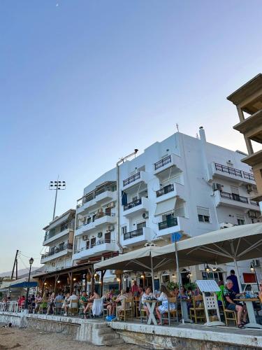 a large white building with people sitting outside of it at FiloXenia by the Sea in Agios Nikolaos