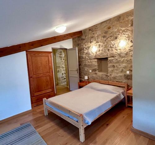 a bedroom with a bed and a stone wall at Mas Chantequinson in Les Assions
