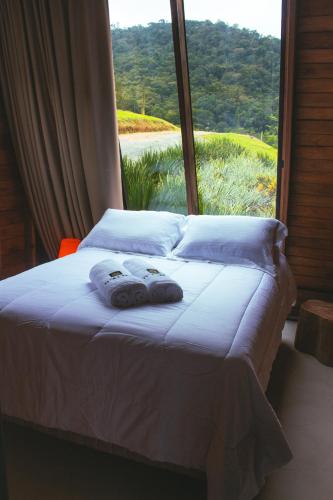 a bed with towels on it in front of a window at D'Alma Chalé com café da manhã in Pomerode