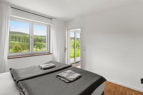 ein weißes Zimmer mit einem Bett und zwei Fenstern in der Unterkunft Neubau! Ökologischer Wellnessurlaub in der Eifel in Kopp
