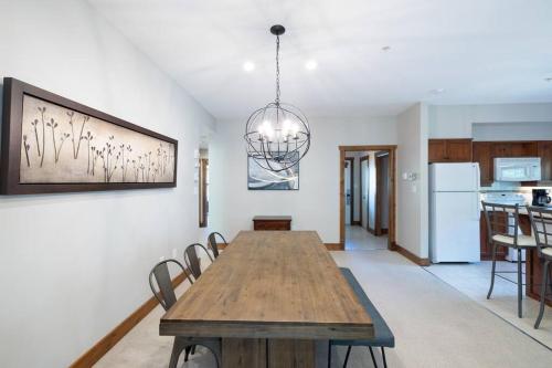 a dining room with a wooden table and a chandelier at Les Eaux Tremblant - Luxury Chalet with Pool & Spa and AC in Mont-Tremblant