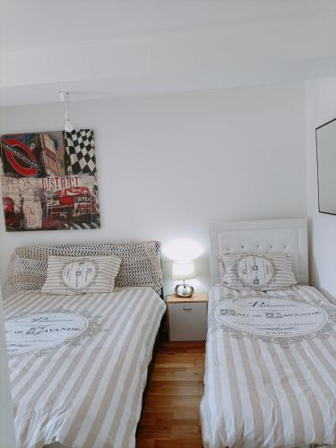- une chambre avec 2 lits et une lampe sur du parquet dans l'établissement Charmant appartement indépendant, 5 mn de Rouen, avec terrasse, refait à neuf, à Franqueville-Saint-Pierre