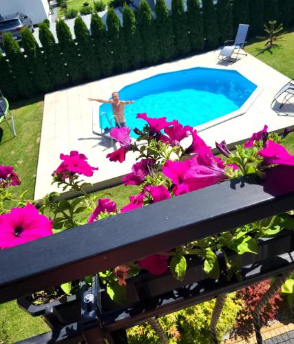a man is sitting in a chair by a swimming pool at Domki i Pokoje u Ilony in Krościenko