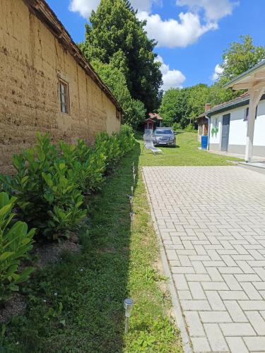 a brick walkway next to a building with a car at Búj-Lak Vendégház in Zalaszentmárton
