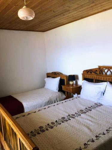 a bedroom with two beds and a table with a lamp at Casa da Avó Clotilde in São Roque do Pico