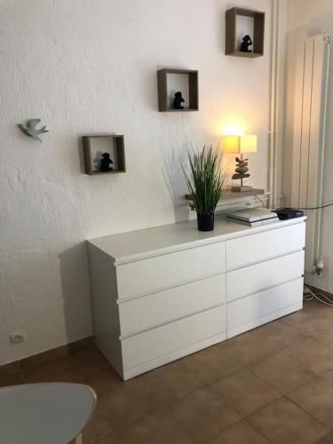 une commode blanche avec une lampe et une plante dessus dans l'établissement Le Rabelais, Studio terrasse, à Nice