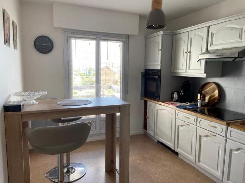 a kitchen with white cabinets and a table with a chair at Joli appartement proche gare in Molsheim