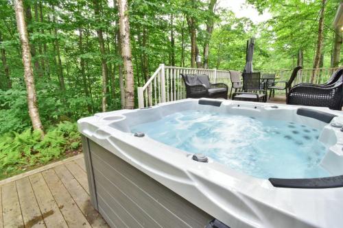 a jacuzzi tub on the deck of a house at Nature retreat with HOT TUB and lake access & watercraft in Saint Adolphe D'Howard
