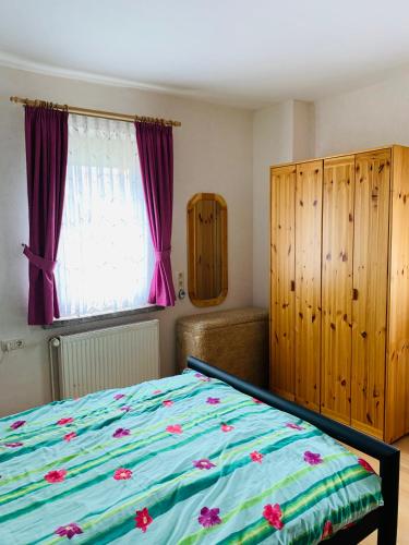 a bedroom with a bed and a window with purple curtains at Ferienwohnung Juttchen in Roßleben