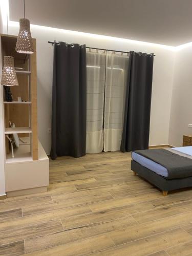 a bedroom with black curtains and a wooden floor at 180 Pool Villa in Anavissos